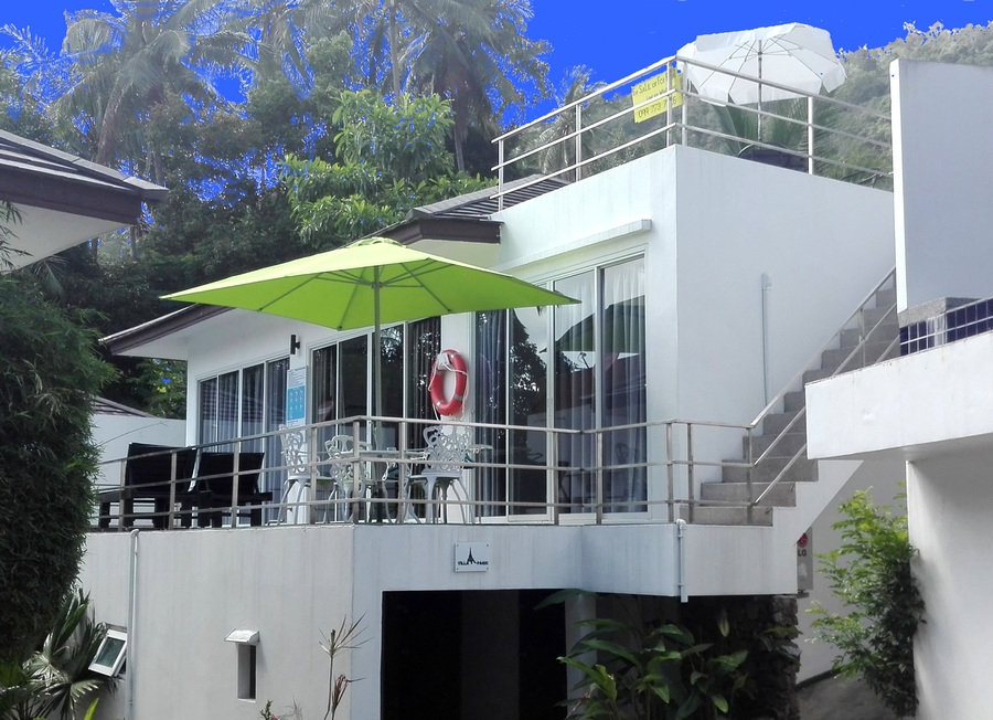 the exterior seen from the stone path on the terrace with swimming pool, parasol, garden furniture